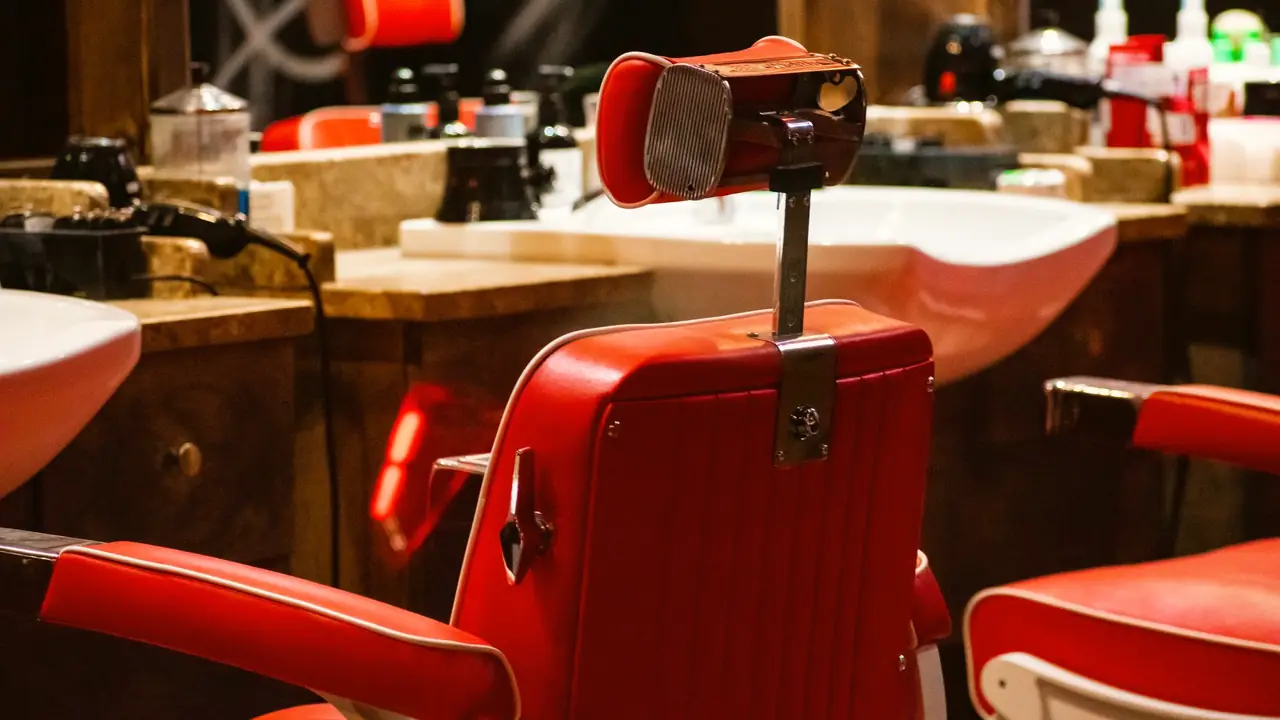 Red barber chairs in front of wash basins