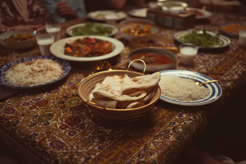 Biryani in a steel pot with a bowl of curry