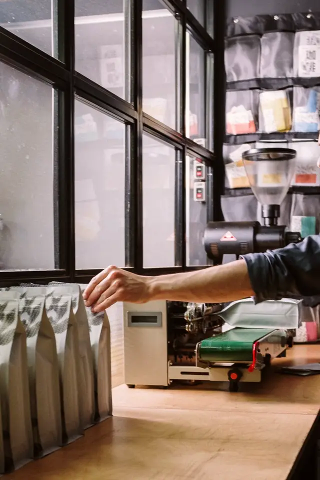 Sealing bags of coffee by the workshop window